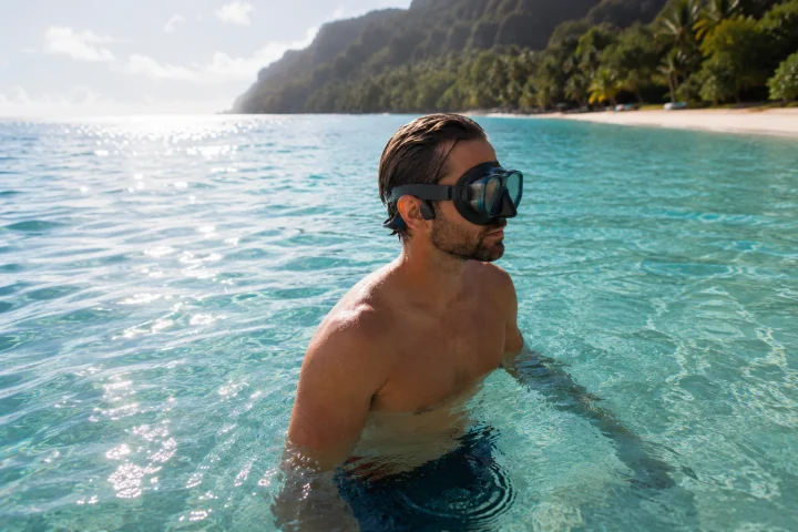 A swimmer in clear Hawaiian water wearing a SubMergence headset