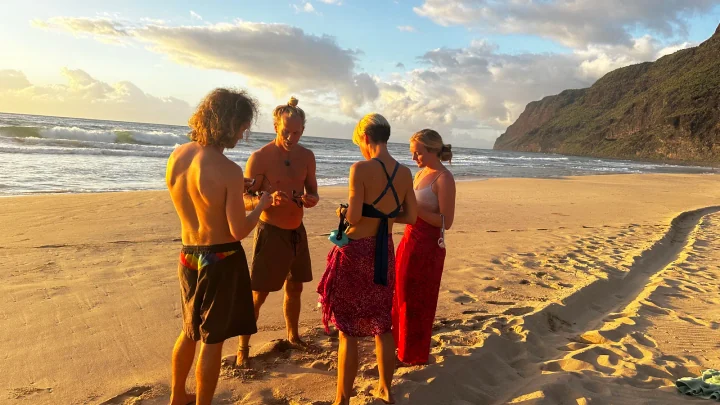 SubMergence founder Alex demonstrating a waterproof headset to a small group on a Kaua'i beach at sunset